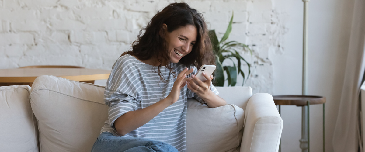 Image of woman sitting on couch looking at phone