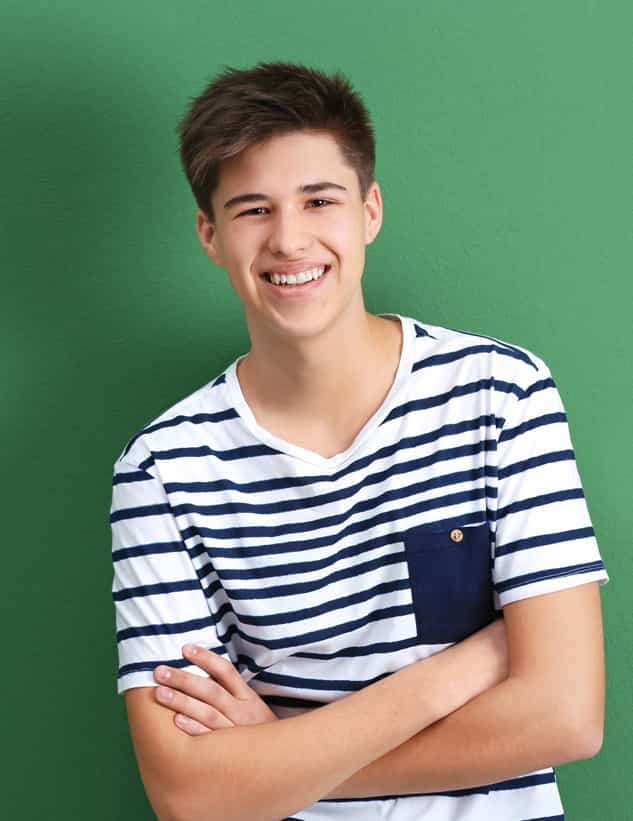 Young teen male standing in front of green background