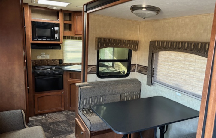 Inside image of dining area of camper. Table next to door.
